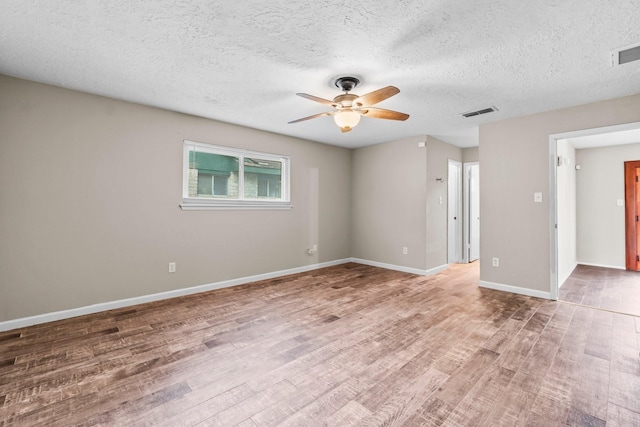 unfurnished room featuring a ceiling fan, wood finished floors, visible vents, and baseboards