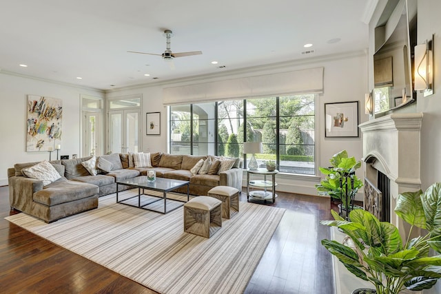 living area featuring visible vents, ornamental molding, dark wood-style floors, a fireplace, and ceiling fan