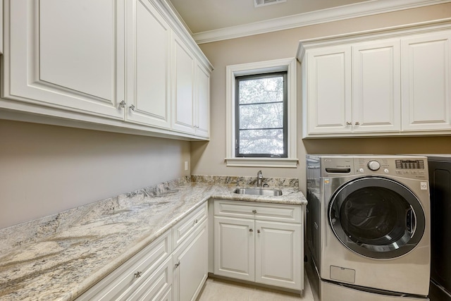 clothes washing area featuring visible vents, a sink, cabinet space, crown molding, and washing machine and clothes dryer