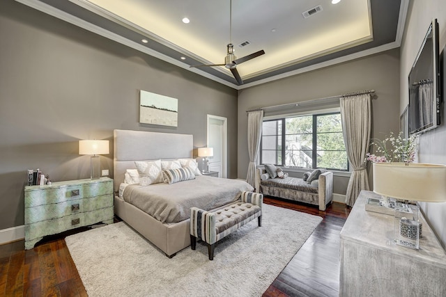 bedroom with dark wood-style floors, visible vents, crown molding, and a raised ceiling