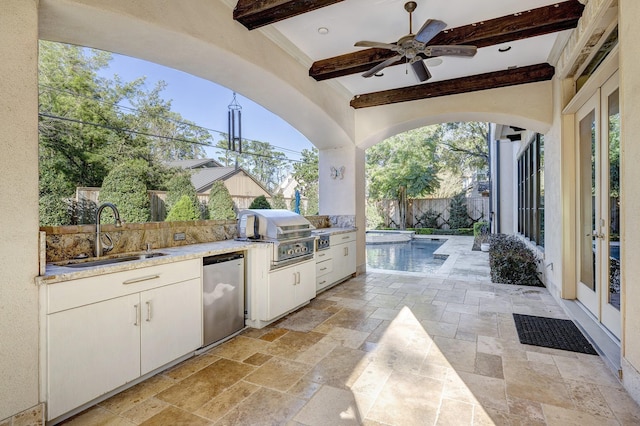 view of patio featuring fence private yard, an outdoor kitchen, a grill, a ceiling fan, and a sink