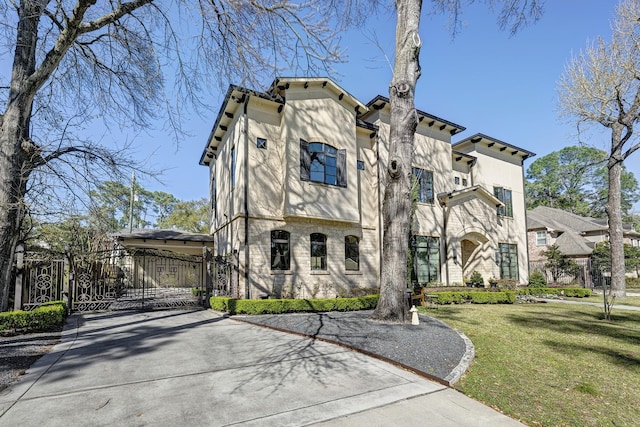 view of front facade featuring fence, a front yard, stucco siding, driveway, and a gate