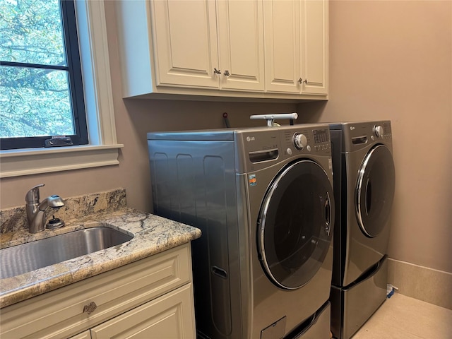 clothes washing area featuring a sink, cabinet space, and separate washer and dryer