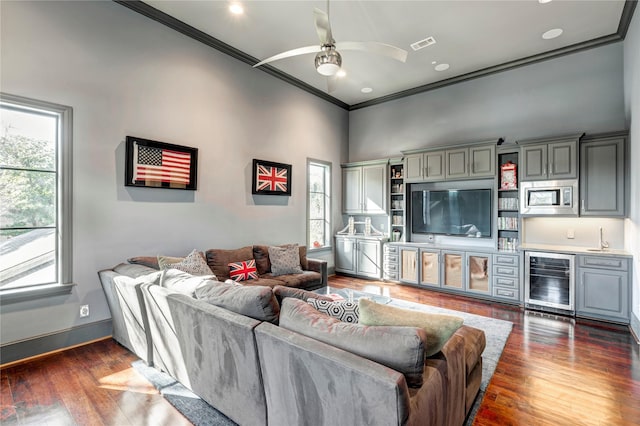 living room featuring wine cooler, visible vents, crown molding, and wood finished floors