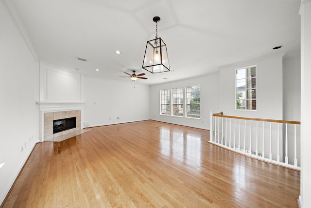 unfurnished living room with visible vents, light wood-style flooring, a fireplace, and ornamental molding