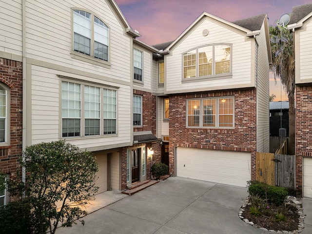 townhome / multi-family property featuring a garage, brick siding, and driveway