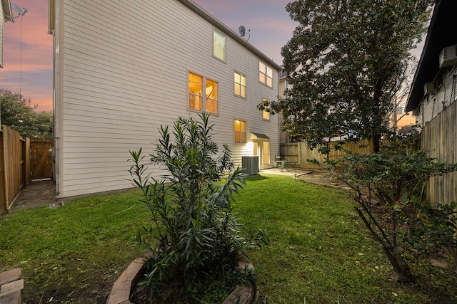 exterior space with a fenced backyard, cooling unit, and a yard