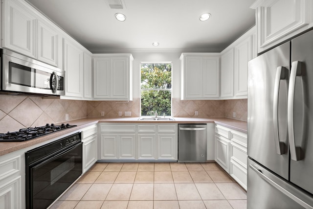 kitchen with light tile patterned flooring, a sink, black appliances, light countertops, and white cabinetry