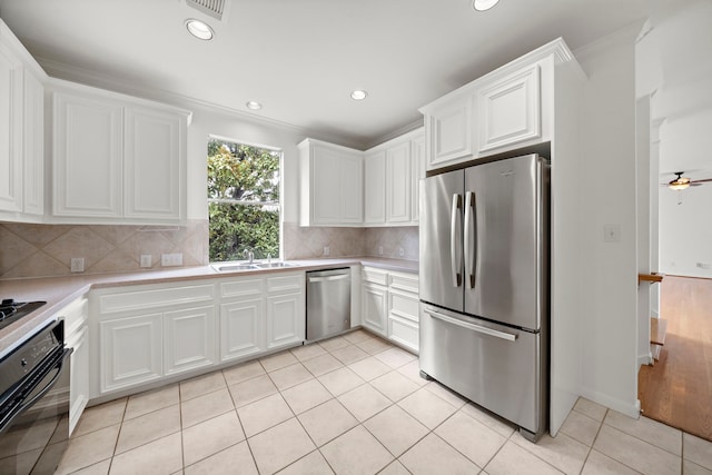 kitchen with light tile patterned floors, a sink, black appliances, light countertops, and white cabinetry