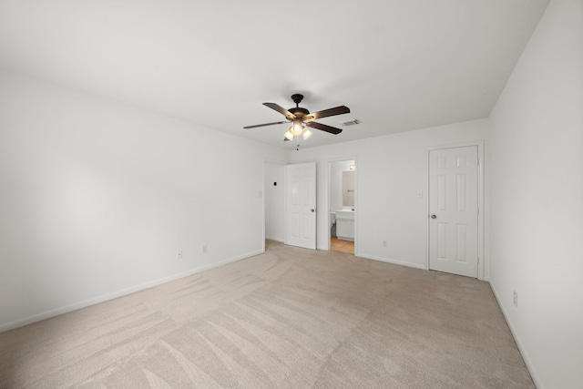 unfurnished bedroom with visible vents, light carpet, connected bathroom, baseboards, and ceiling fan