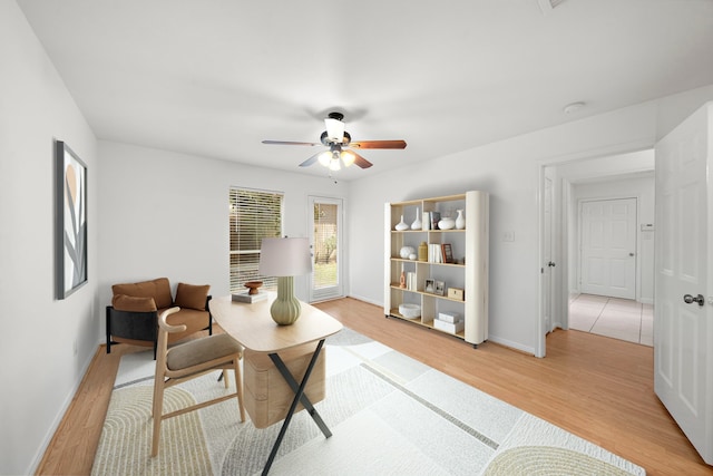 sitting room featuring baseboards, light wood-style floors, and a ceiling fan