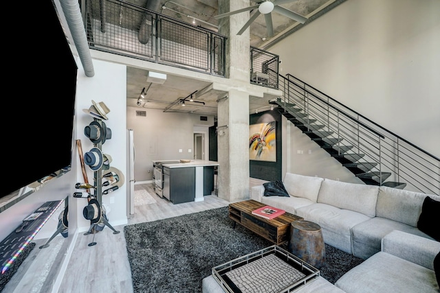 living room featuring stairs, visible vents, ceiling fan, light wood-style flooring, and baseboards