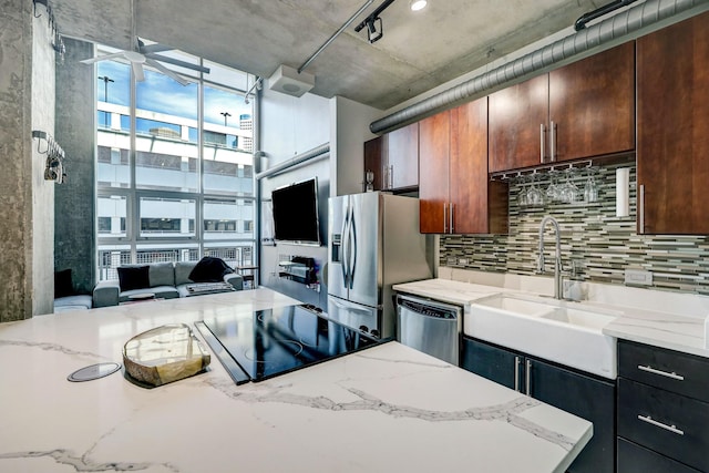 kitchen featuring a sink, light stone counters, ceiling fan, decorative backsplash, and appliances with stainless steel finishes
