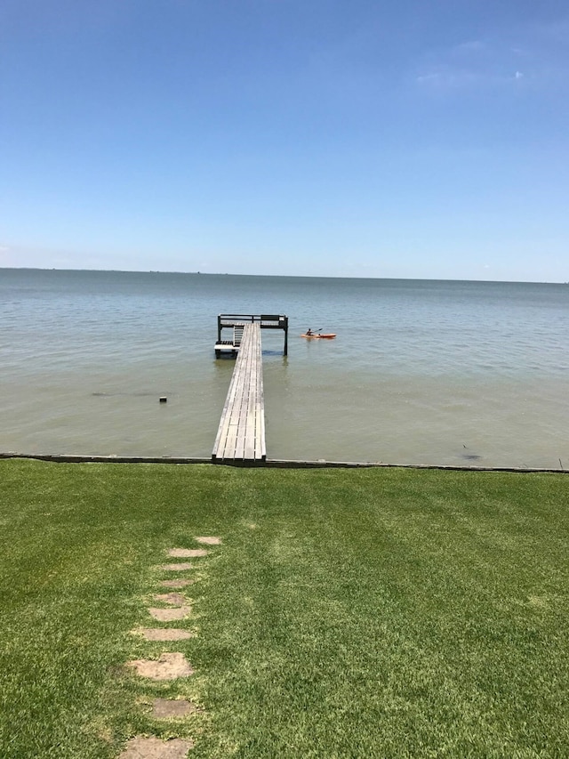 view of dock with a lawn and a water view