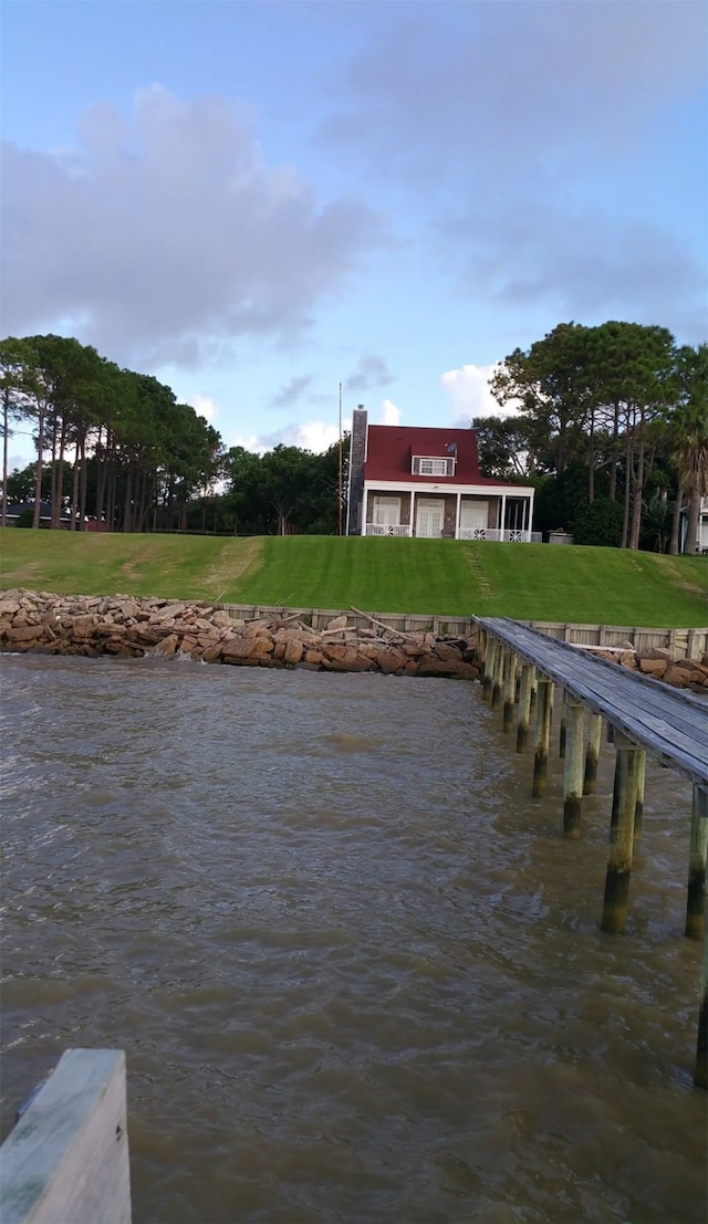 dock area with a lawn and a water view