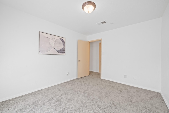 empty room with baseboards, visible vents, and carpet flooring