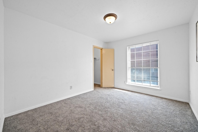 unfurnished room with carpet and baseboards