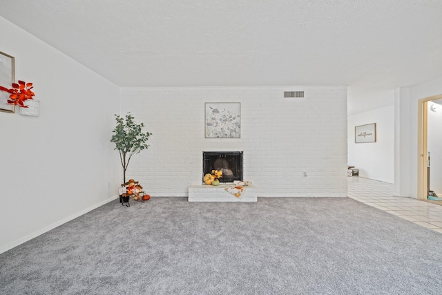 unfurnished living room with carpet floors, brick wall, a fireplace, and visible vents