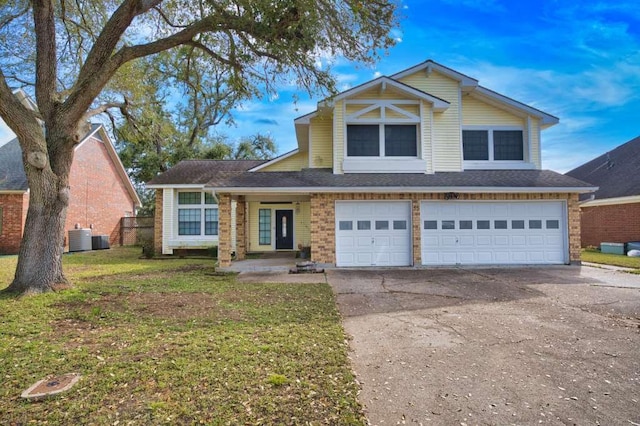 view of front of home featuring brick siding, an attached garage, a front yard, cooling unit, and driveway