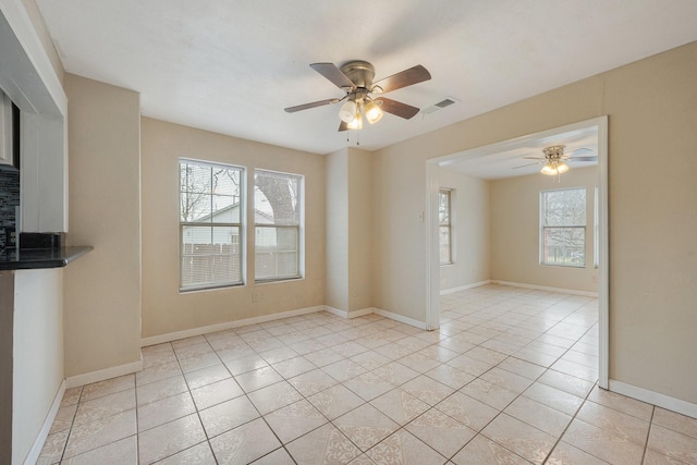 empty room with light tile patterned floors, visible vents, baseboards, and ceiling fan