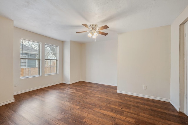 empty room featuring a ceiling fan, dark wood finished floors, and baseboards