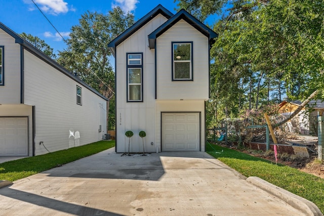 view of front of property with board and batten siding, cooling unit, driveway, and a garage