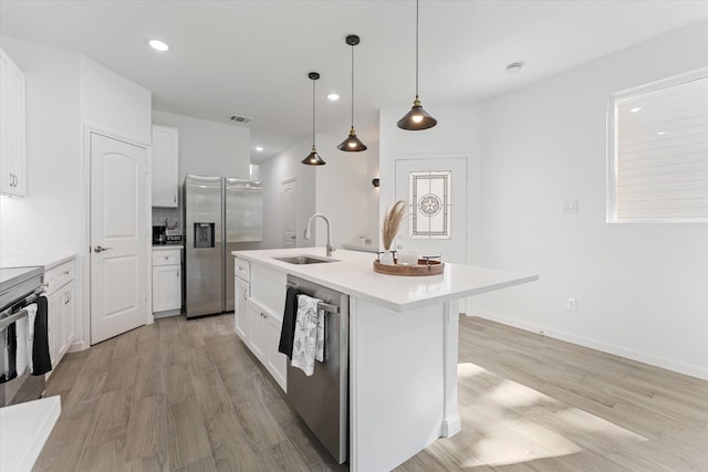 kitchen with appliances with stainless steel finishes, light wood-style floors, white cabinets, and a sink