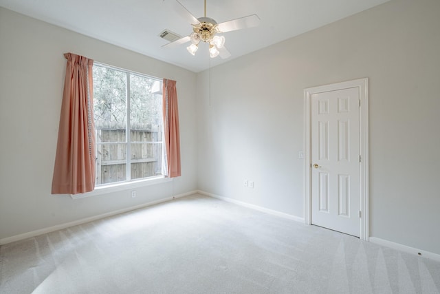 carpeted empty room with a ceiling fan, visible vents, and baseboards