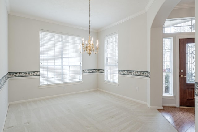 entryway with arched walkways, crown molding, carpet floors, baseboards, and an inviting chandelier