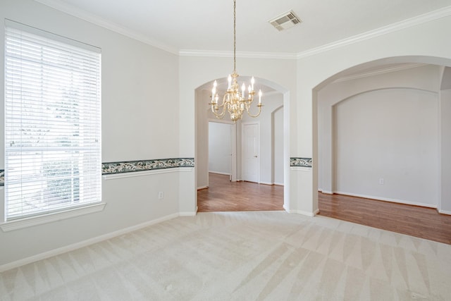 unfurnished room with carpet, a notable chandelier, visible vents, ornamental molding, and baseboards