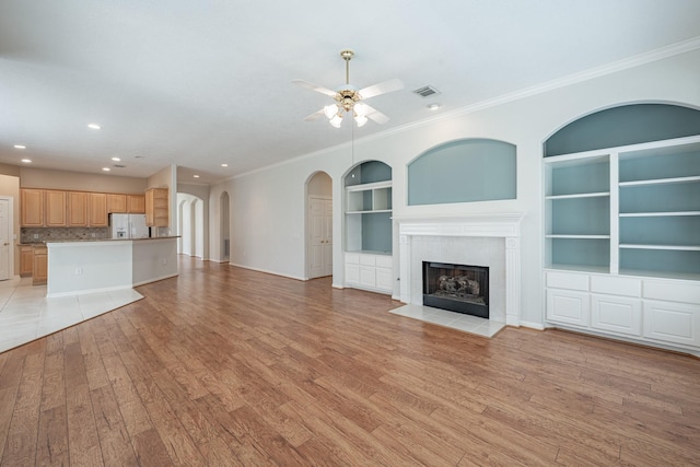 unfurnished living room featuring visible vents, a fireplace with flush hearth, ornamental molding, ceiling fan, and light wood-type flooring