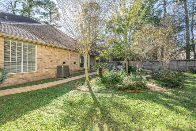 view of yard featuring central AC and fence