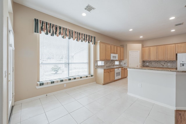 kitchen featuring white appliances, light brown cabinets, visible vents, and backsplash