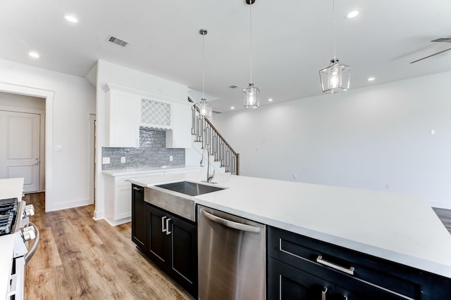 kitchen with decorative light fixtures, tasteful backsplash, appliances with stainless steel finishes, light wood-style floors, and a sink