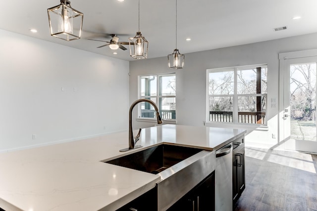 kitchen featuring a sink, plenty of natural light, dark cabinets, and decorative light fixtures