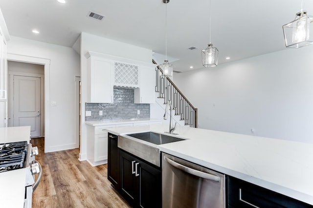 kitchen featuring a sink, visible vents, appliances with stainless steel finishes, decorative backsplash, and decorative light fixtures