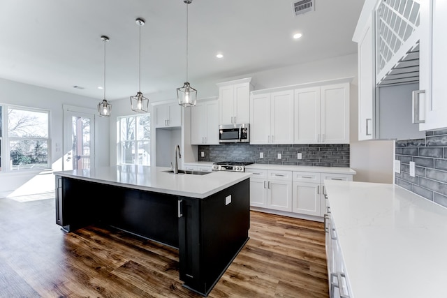 kitchen featuring a sink, visible vents, light countertops, range, and stainless steel microwave