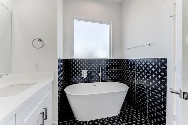 full bathroom with a soaking tub, vanity, and tile walls