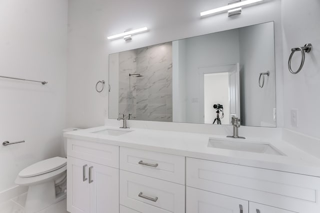 bathroom featuring a walk in shower, double vanity, a sink, and toilet