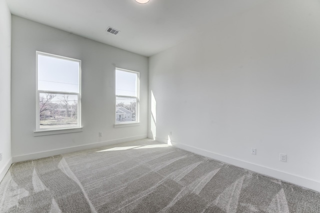 carpeted spare room with baseboards and visible vents