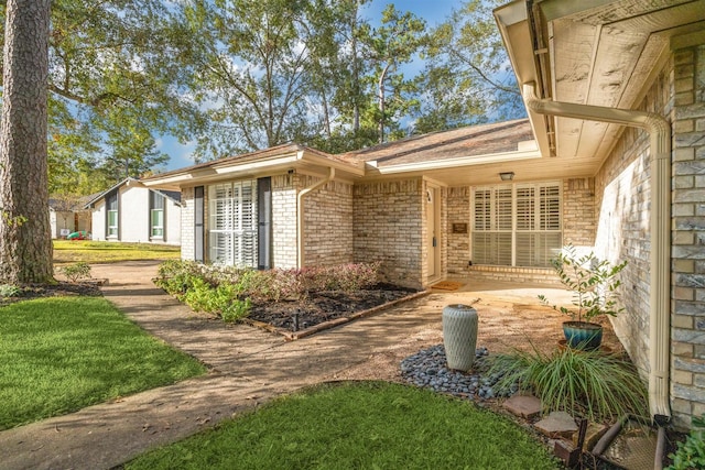 property entrance with brick siding and a lawn