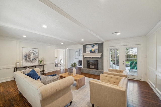 living room with visible vents, a decorative wall, wood finished floors, and ornamental molding