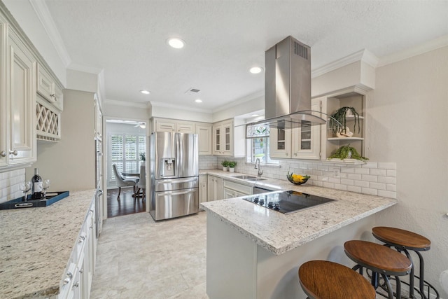 kitchen featuring black electric cooktop, island range hood, a peninsula, a sink, and stainless steel fridge