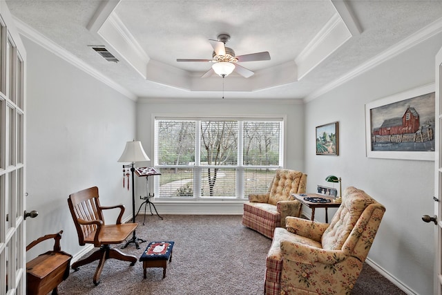 sitting room with ornamental molding, a tray ceiling, a textured ceiling, and carpet