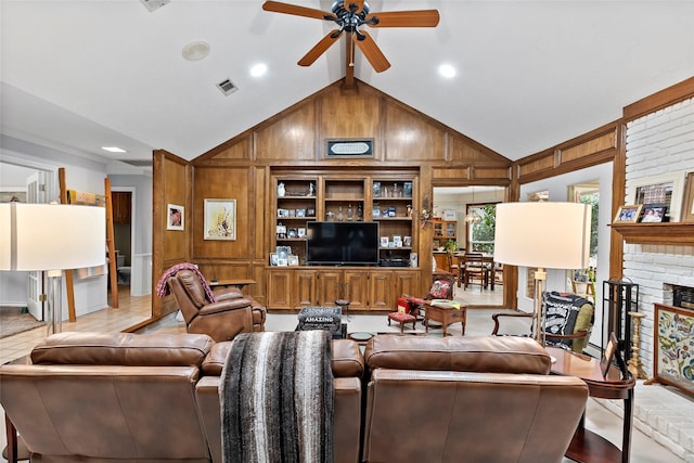 living area featuring lofted ceiling, wood walls, a fireplace, visible vents, and a ceiling fan