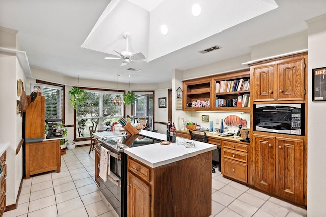 kitchen featuring ceiling fan, a kitchen island, visible vents, light countertops, and double oven range