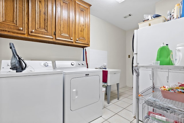 clothes washing area featuring visible vents, washer and clothes dryer, light tile patterned flooring, and cabinet space