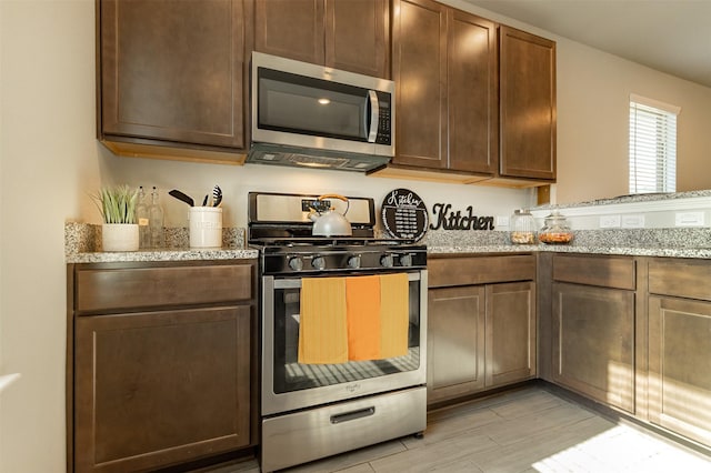 kitchen with stainless steel appliances, light wood finished floors, and light stone countertops