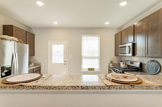 kitchen featuring stainless steel appliances, dark brown cabinets, light countertops, and recessed lighting