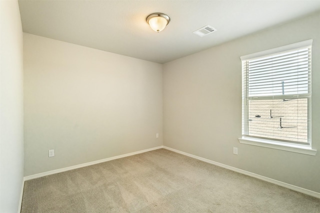 spare room with light carpet, visible vents, and baseboards